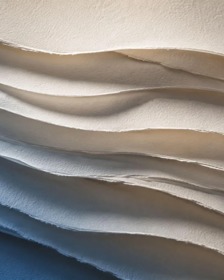 Helle Lagen aus handgeschöpftem Papier, die in sanften Wellen übereinanderliegen